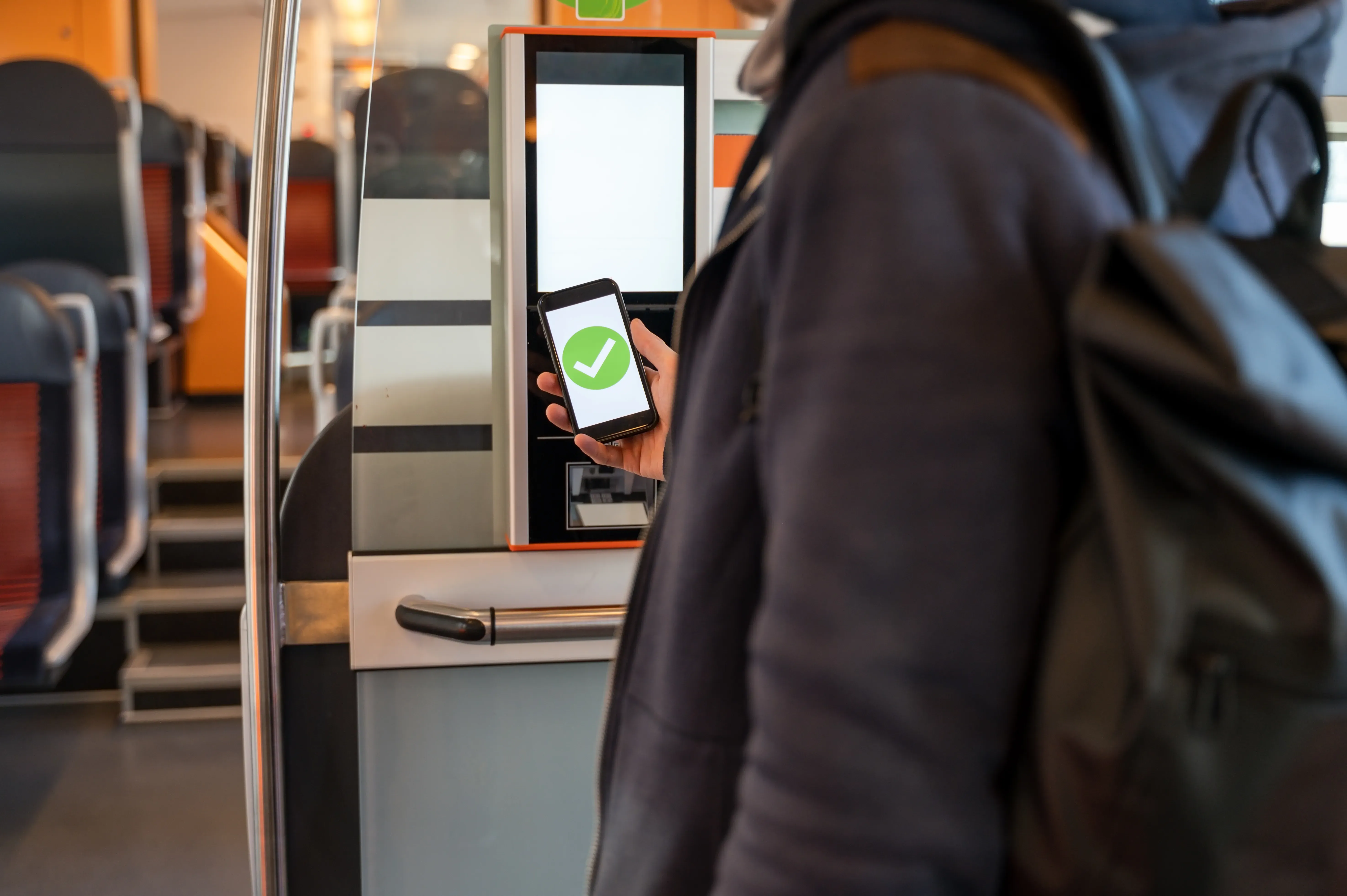 Eine Frau hält im Zug ihr Smartphone vor ein Lesegerät.