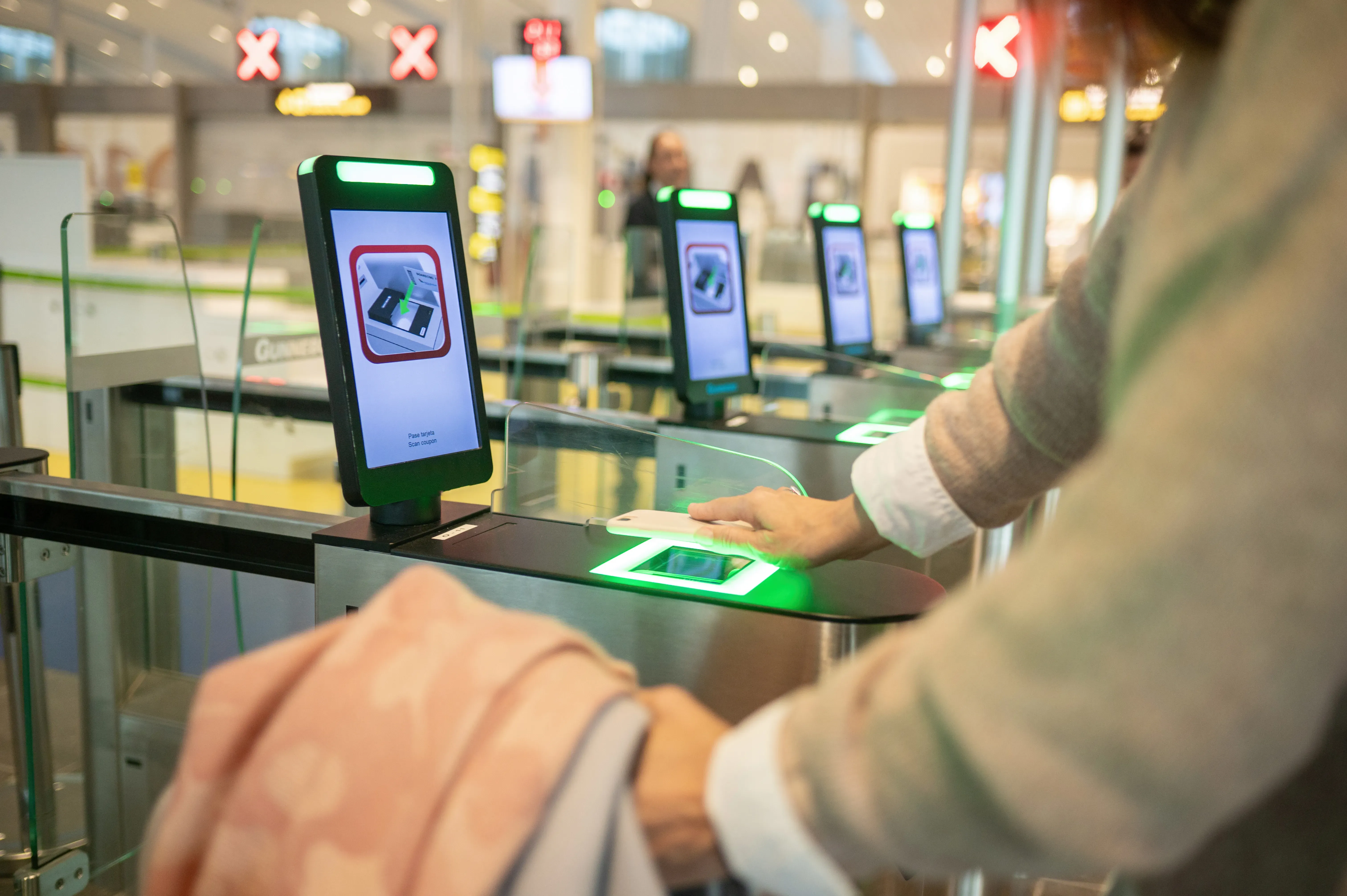 A woman holds her smartphone over a scanner at the airport.