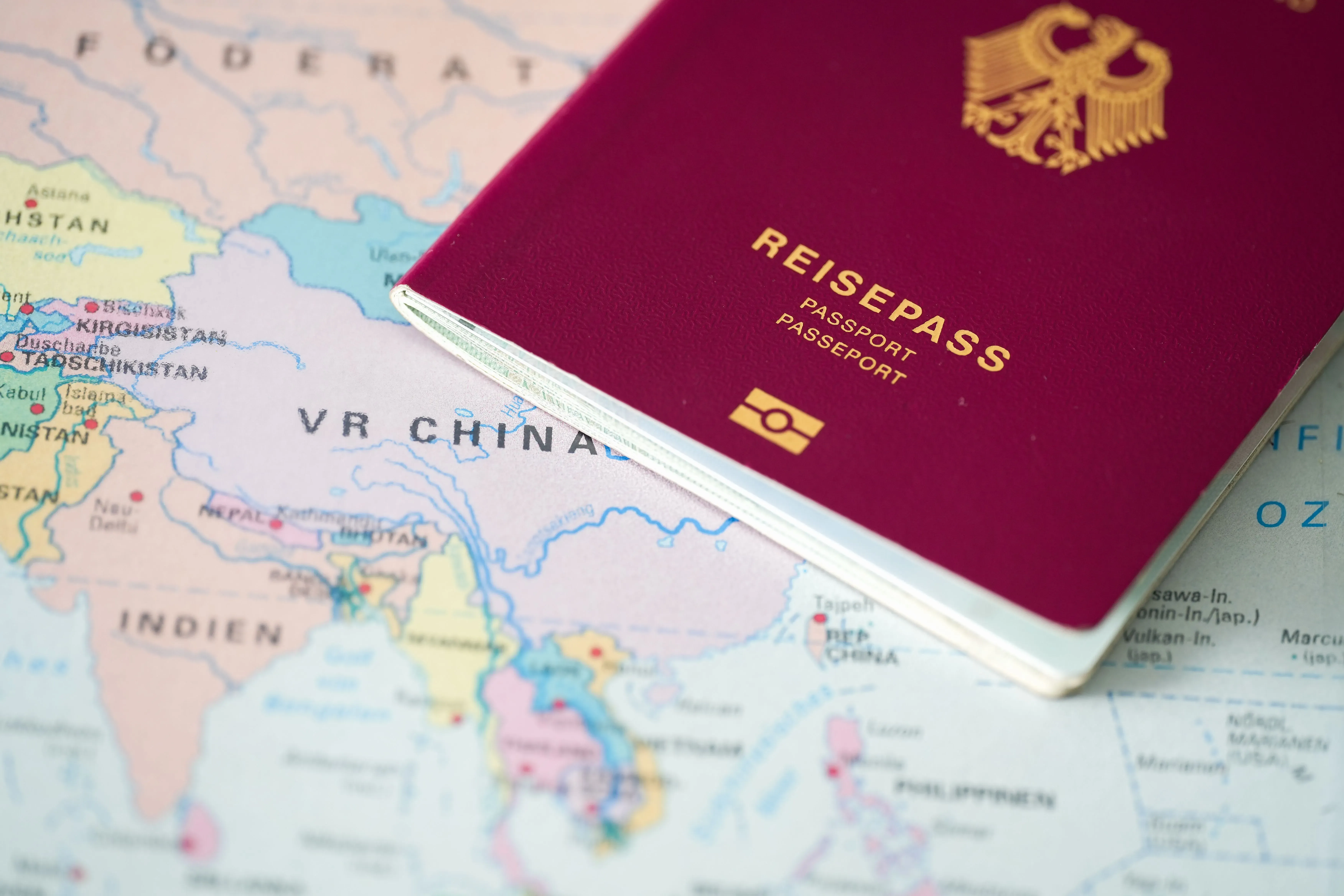 A burgundy-coloured German passport lies on a map of the world, and the golden ICAO symbol is visible.