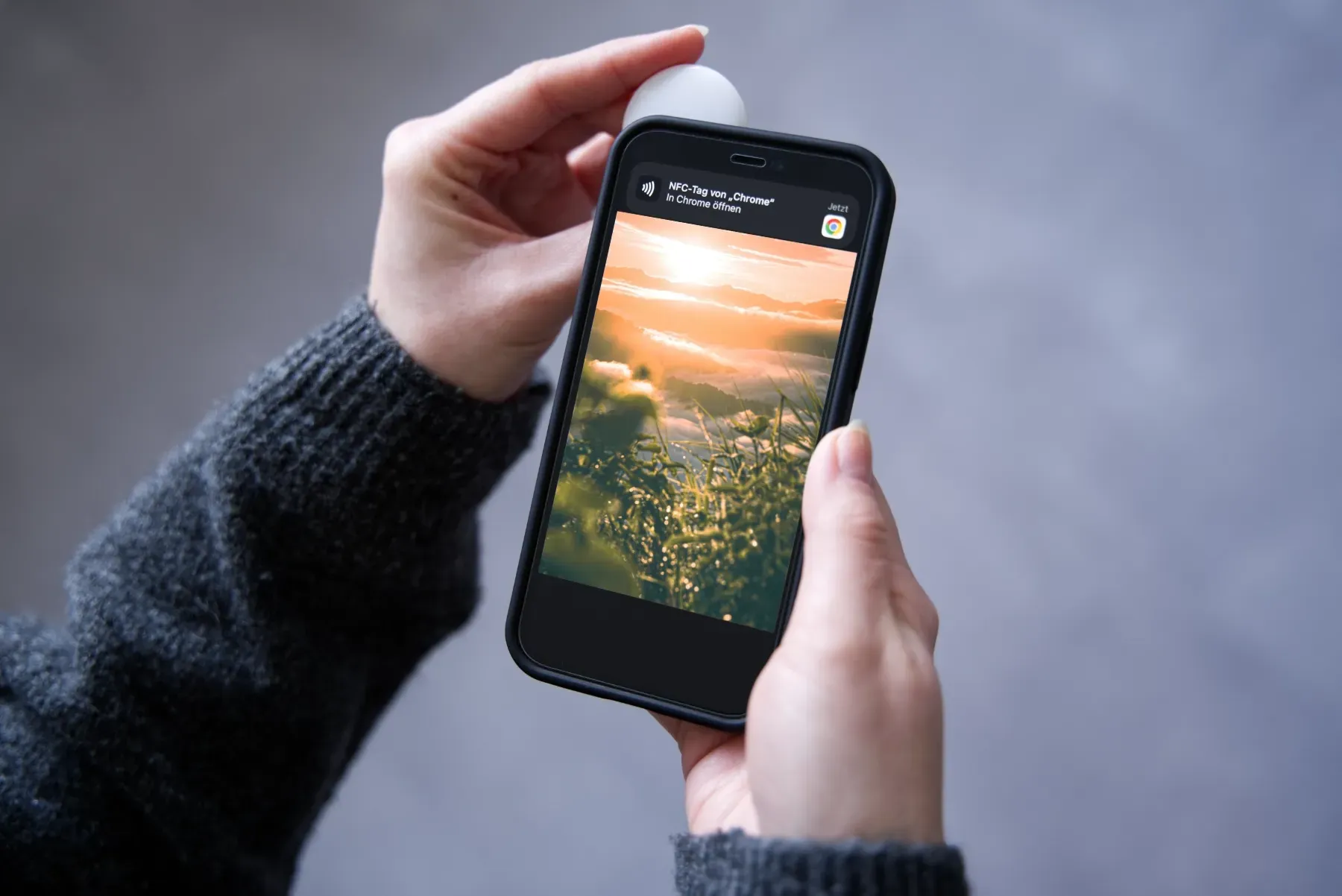 Hand hält AirTag in der oberen linken Ecke eines iPhones