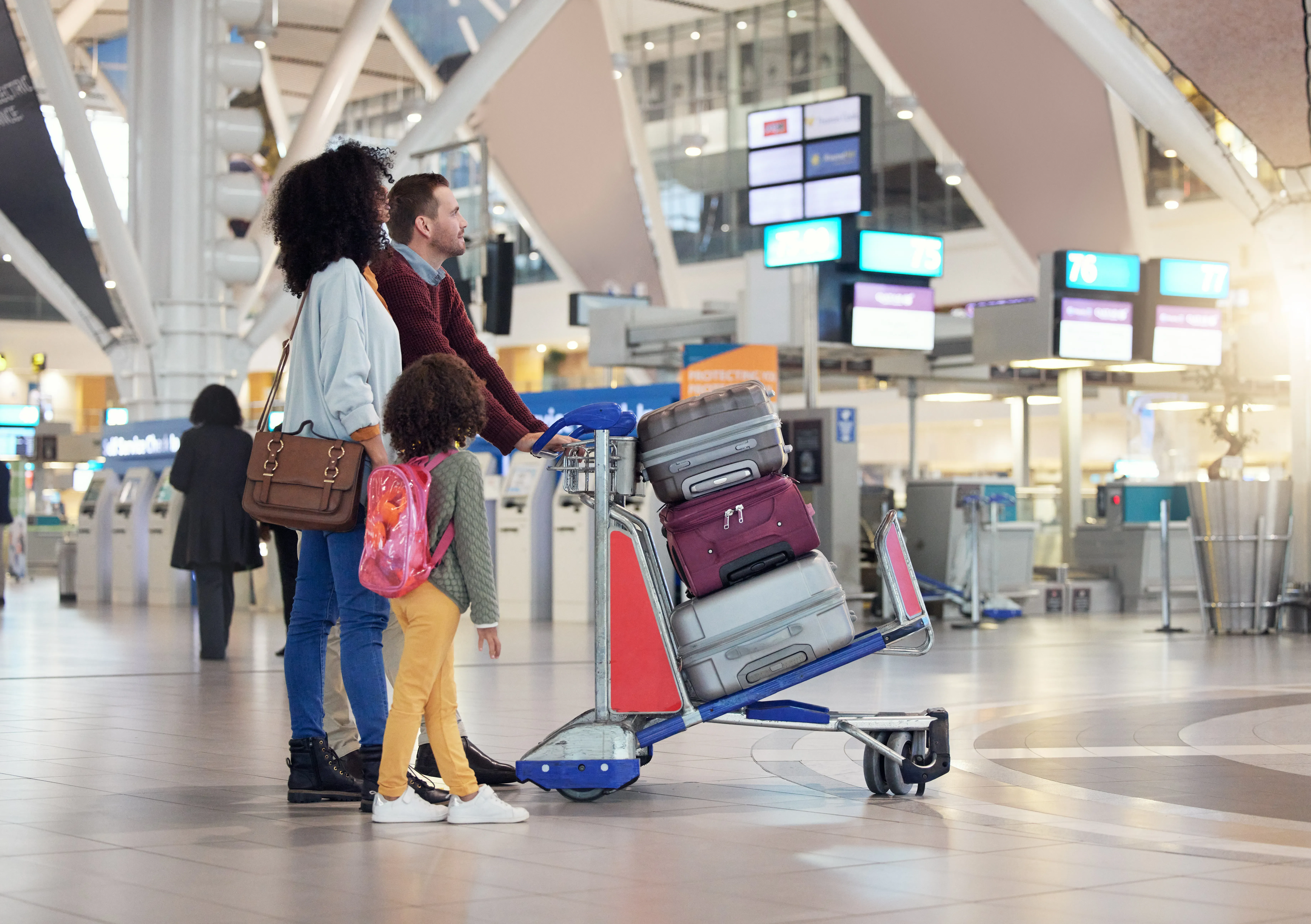 A family is at the airport, carrying several suitcases, a handbag and a rucksack.